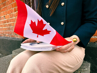 Woman holding Canada flag and notebook, symbol of immigration and new beginning