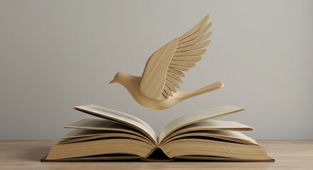 Wooden bird sculpture flying above an open book on a light wood table against a plain gray wall