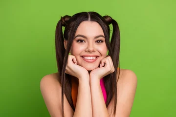 Fotobehang Bright young woman with trendy ponytails posing against a vibrant green background exuding positivity and youthful charm © deagreez