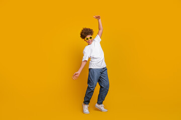 Stylish young boy in casual outfit posing against yellow backdrop, expressing joy and energy with...