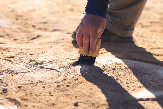Senior man using wooden brush sweeping dirt from chalk line on baseball infield, copy space
