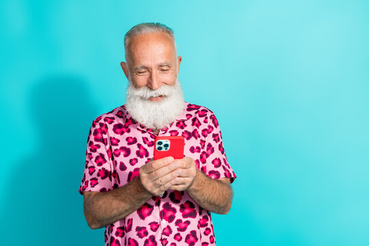 Photo of attractive senior bearded man hold telephone dressed stylish pink leopard print clothes isolated on cyan color background - Powered by Adobe