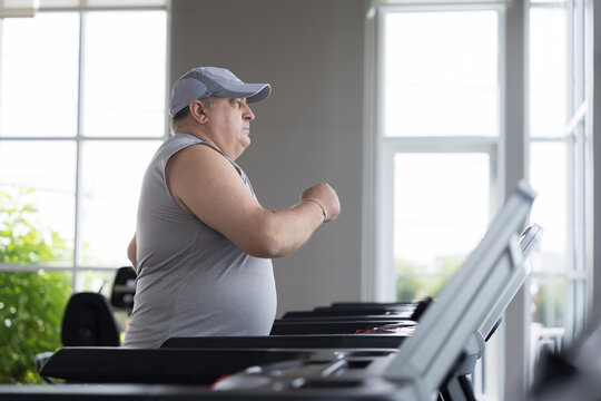 Man running on treadmill in gym. Mature male running on treadmill machine. Fitness, gym and exercising