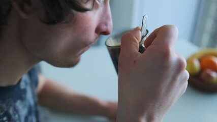 Overhead shot of a young man sitting at a kitchen table, drinking black coffee and eating oatmeal with bread. Cozy homemade breakfast in casual atmosphere, captured in natural light.  - Powered by Adobe