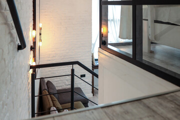 White painted staircase with black metal railing, descending into a bright living room with white...