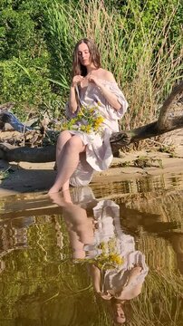 Ukrainian girl in wreath poses near water.
