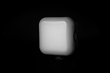 A square LED panel with soft light is displayed on a dark background. The panel emits a cool light...
