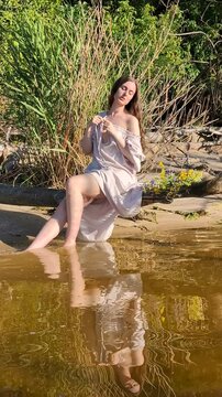 Ukrainian girl in wreath poses near water.
