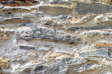 Close-up of an ancient stone wall showing rough slate layers and rustic mortar, perfect for backgrounds, architectural or construction design themes.