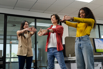 Diverse coworkers doing wrist and shoulder stretch in glass office with monitor showing turbines