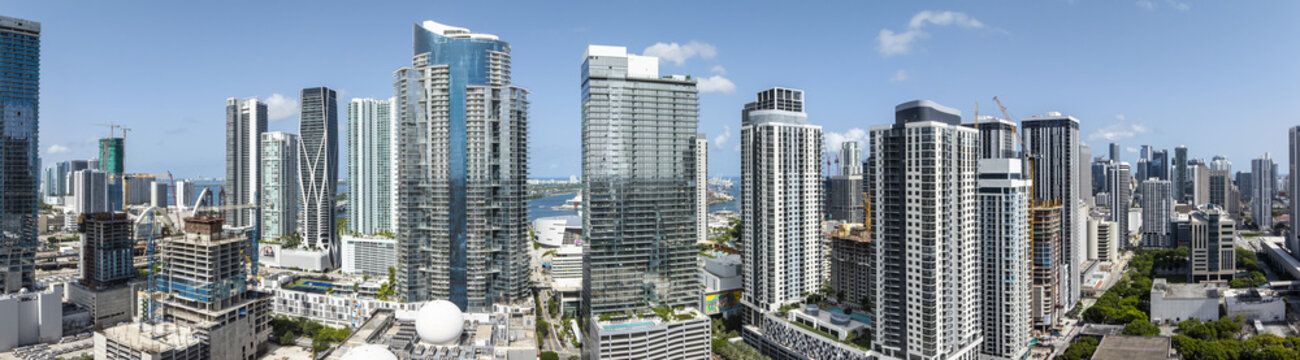 Aerial view of the city's skyline with sleek skyscrapers piercing the clear blue sky, juxtaposed with verdant patches of green, Miami, Florida, United States.