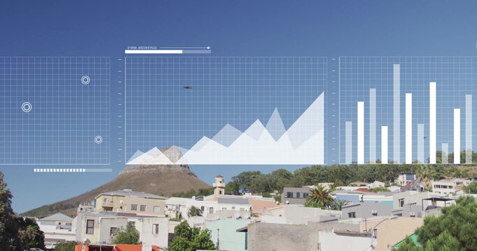 Displaying digital grid, area and bar charts hovering above hillside area, pastel houses, drone