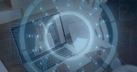 Man taking notes in notebook at desk, laptop displaying meeting with interface graphics overlaying