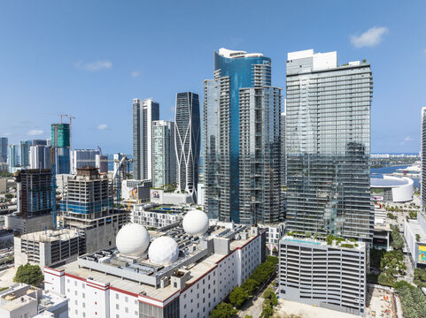 Aerial view of gleaming skyscrapers piercing the bright blue sky, contrasting with the geometric patterns of the buildings below, Miami, Florida, United States.