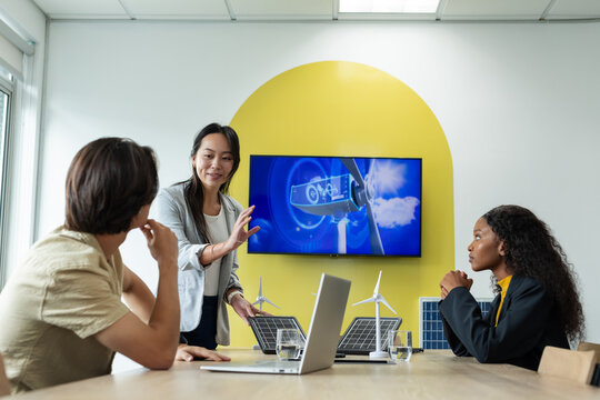 Diverse coworkers presenting wind turbine diagram on screen in conference room with laptop, models - Powered by Adobe