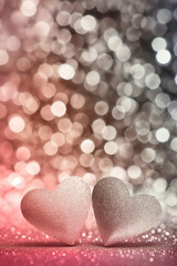 Fototapeta premium Two glitter hearts in pink and grey tones with warm bokeh lights. Romantic and cozy background for Valentine's day.