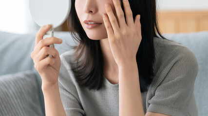 鏡で肌をチェックする女性