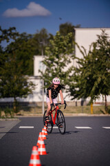 Obraz premium Young Girl Riding Bike Through Traffic Cones on Sunny Day