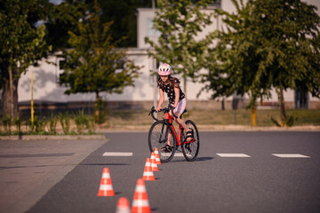 Naklejka premium Girl Practicing Bike Skills on City Road with Cones