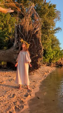 Ukrainian girl in wreath poses near water.
