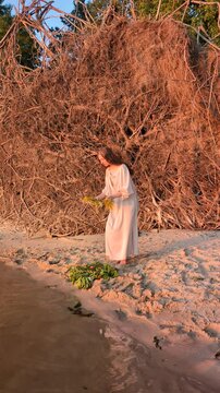Ukrainian girl in wreath poses near water.
