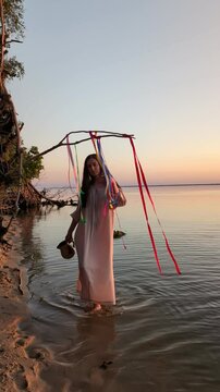 Ukrainian girl in wreath poses near water.
