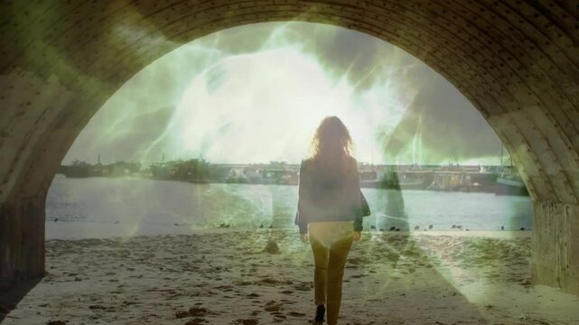 Woman walking through stone arch onto sandy beach as emerging green energy portal animating AR demo