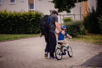 Parent Teaching Young Child to Ride Bike on Sidewalk