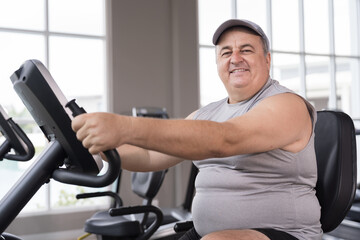 Man exercise bike in gym. Mature male workout biking in gym. Exercising legs. Fitness, gym and exercising