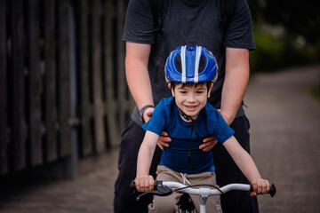 Parent Teaching Young Child to Ride Bike on Sidewalk