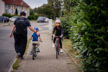 Girl Cycling on Sidewalk as Sibling Learns to Ride Nearby