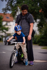 Parent Teaching Young Child to Ride Bike on Sidewalk