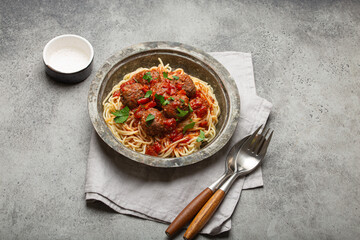 Delicious spaghetti with meatballs and tomato sauce on a rustic table with neatly arranged cutlery...