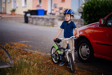 Young Boy Picking Up Fallen Bicycle on Side of Street