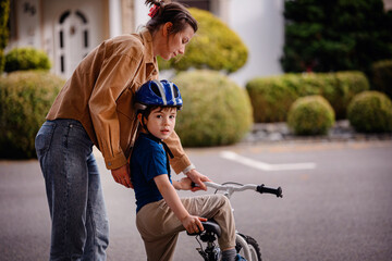 Woman Teaching Young Boy to Ride Bicycle Outdoors