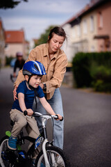 Mother Helping Son Learn to Ride a Bike Outdoors