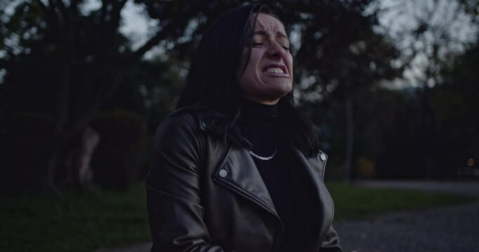 A woman in a dark setting displays intense facial expressions, including puffing cheeks, grimacing, and an open-mouthed scream, conveying raw emotion, pain, and struggle.