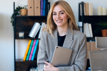 Beautiful lawyer woman working with digital tablet while looking at camera in her modern office
