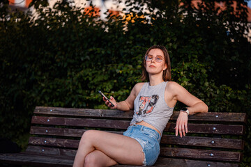 Woman Sitting on Bench Using Smartphone in Summer © Oleksii Yemelianov