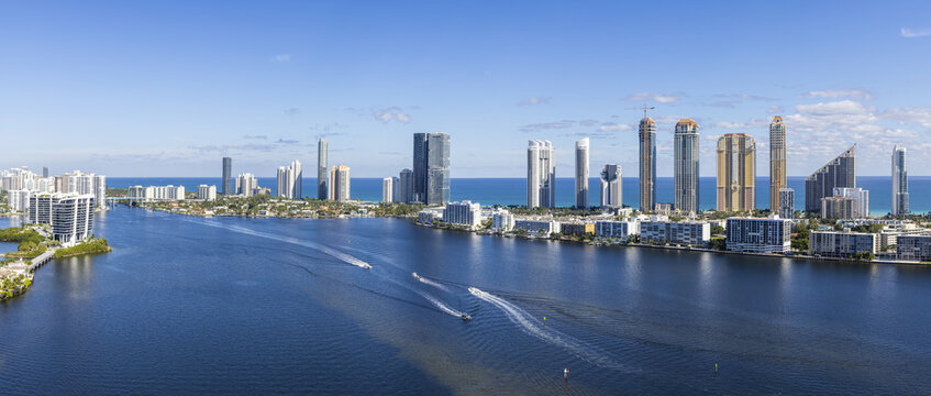 Aerial view of gleaming skyscrapers and winding waterways create a stunning contrast against the clear blue sky, Sunny Isles Beach, Florida, United States.