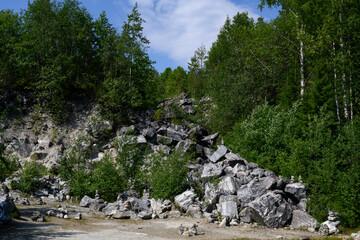 A slope littered with rocks and overgrown with birches and pines in the Ruskeala Mountain Park in Karelia