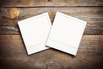 Two blank instant photo frames are placed side by side on a rustic wooden surface, ready for memories to be captured