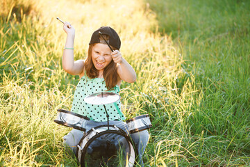 Beautiful smiling happy young little girl with long hair playing on the drums. Expressive Drummer...