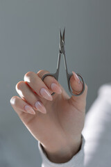 Elegant beige manicure with scissors in hand, professional nail technician work close-up