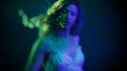 Ethereal underwater portrait of young woman, water-distorted glamorous face in mystical blue tones.