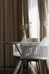 Glass vase with artificial flowers on decorative table in bedroom