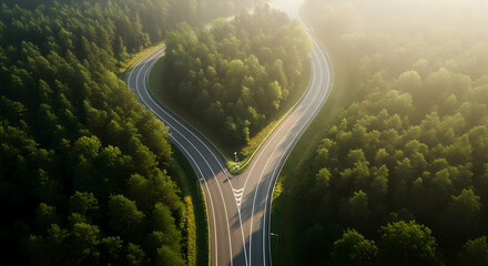 Aerial view of a forked road winding through a lush green forest at sunrise creating a scenic landscape
