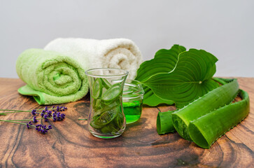 Advertising aloe vera gel in jar against gray. Composition of aloe vera leaves, towels, lavender.