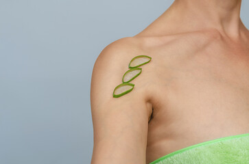 Aloe skin cosmetology. Slices of aloe vera on bare shoulder. Organic cosmetics for spa therapy.