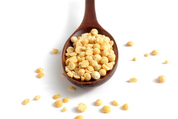 On a white background lies a wooden spoon with dry yellow peas